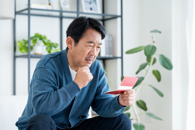 通帳を見て悩む男性